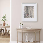Bird wall art print of framefd winter painting. The artwork by Karen Whitworth hangs in a living room with bright airy neutral home decor.