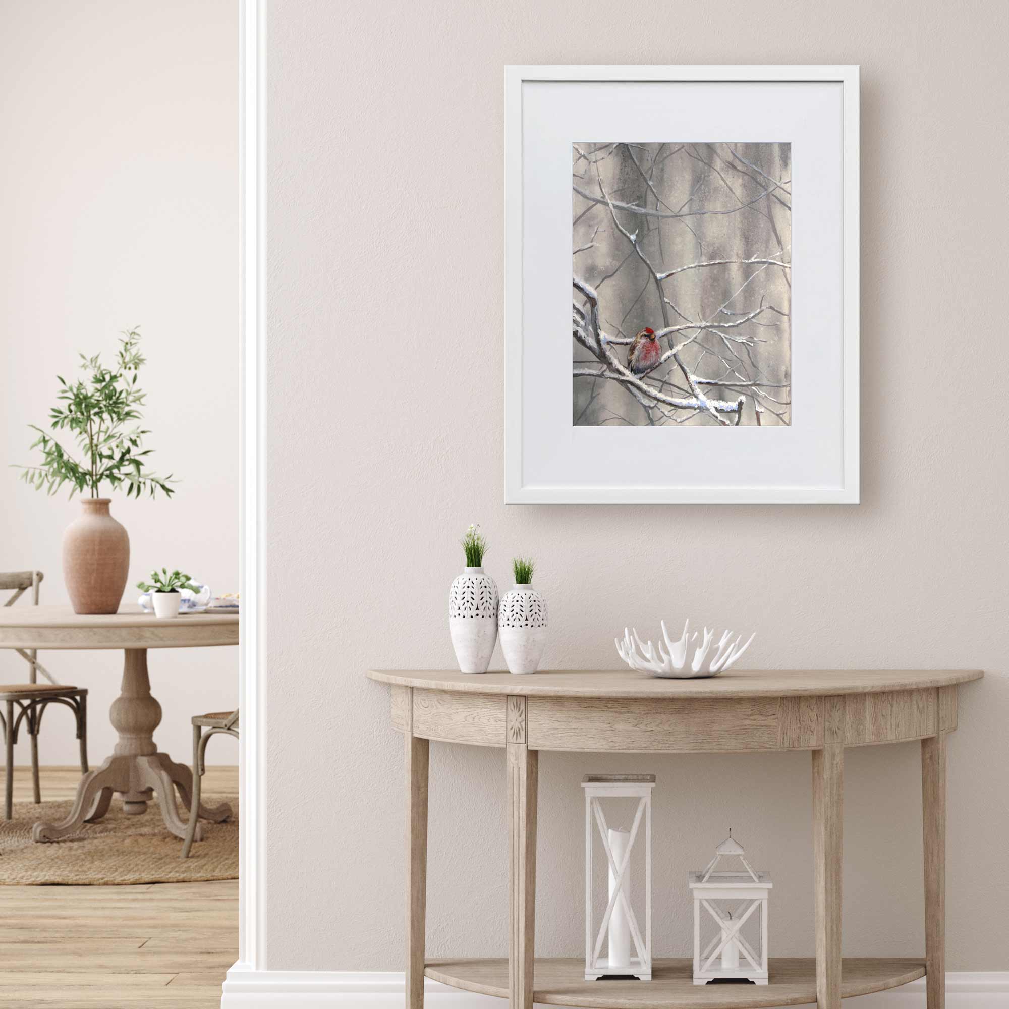 Bird wall art print of framefd winter painting. The artwork by Karen Whitworth hangs in a living room with bright airy neutral home decor.