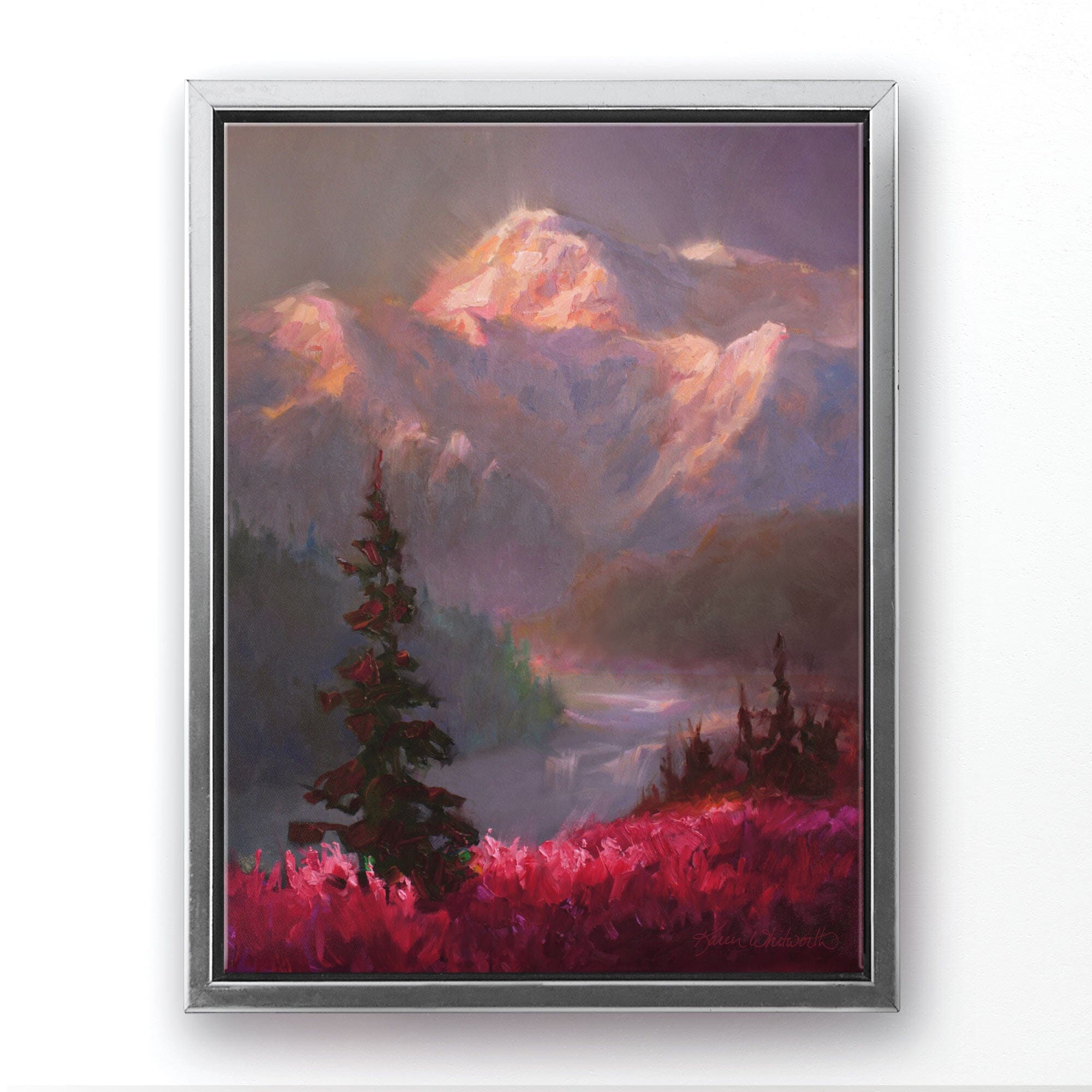 Alaska canvas art of mountain landscape painting depicting Denali in the background and trees and fireweed flowers in the foreground. The wall art is framed in a Silver floater frame and hanging on a white wall.