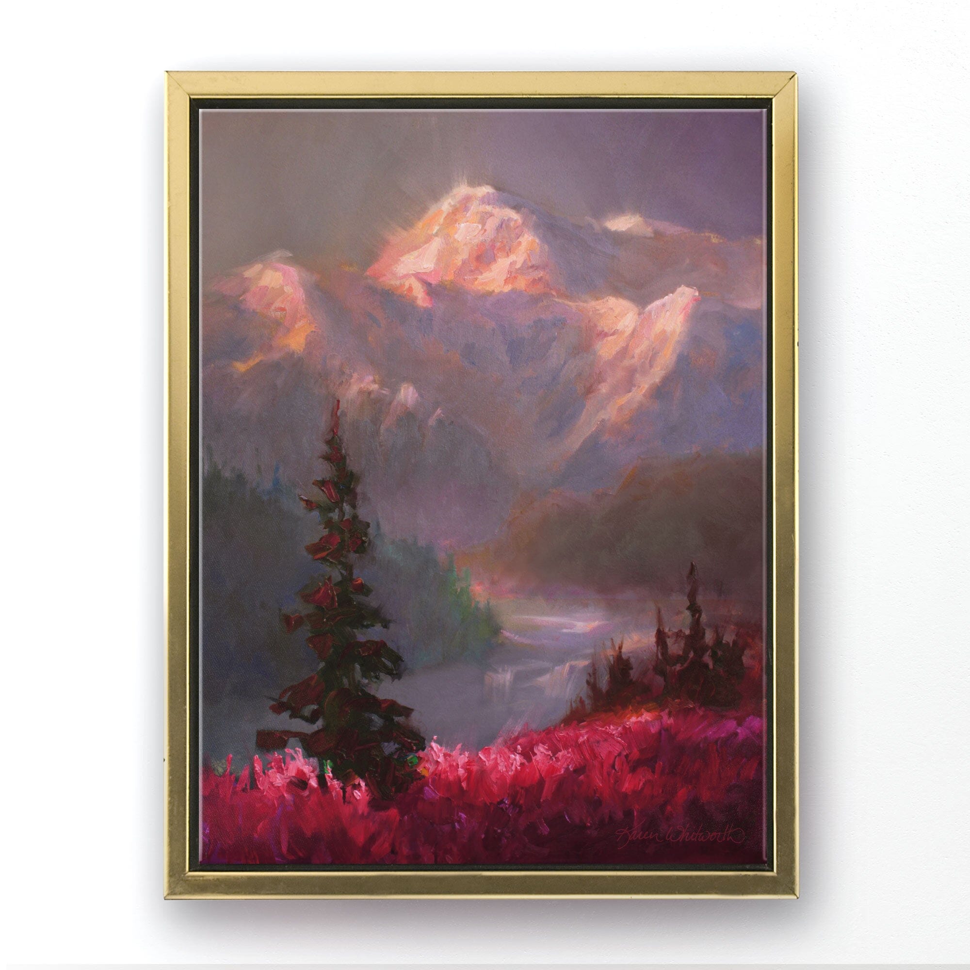 Alaska canvas art of mountain landscape painting depicting Denali in the background and trees and fireweed flowers in the foreground. The wall art is framed in a gold floater frame and hanging on a white wall.