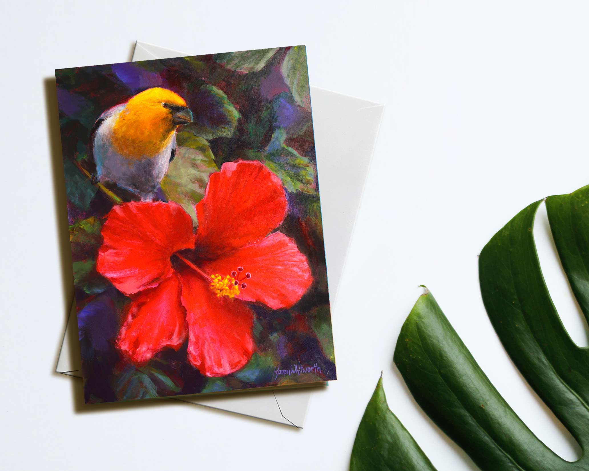An envelope and card featuring art of a tropical Hawaiian Hibiscus flower and an endemic Palila bird on white background