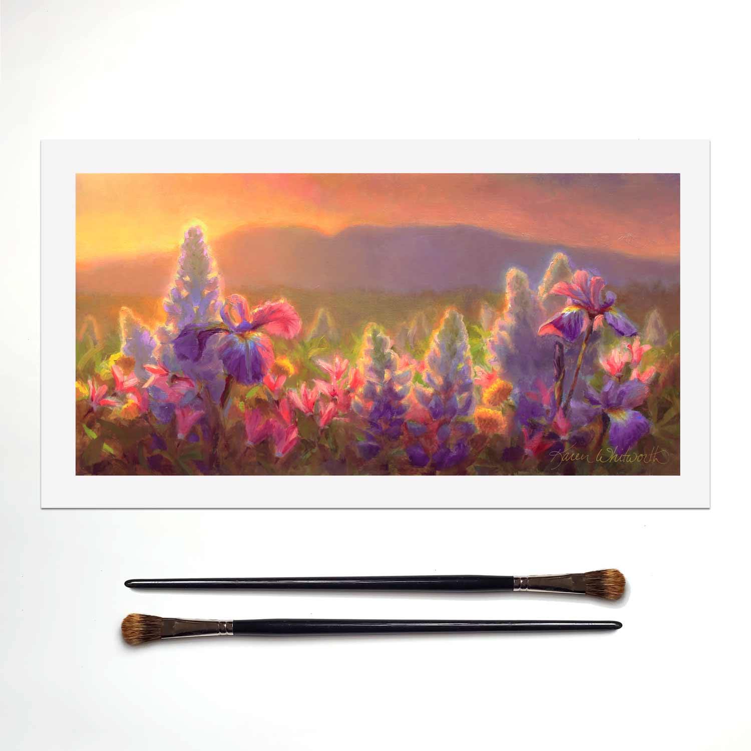 Sleeping Lady Alaska wall art mountain landscape painting of wildflowers and Mt Susitna. The artwork is sitting on a white table next to 2 paintbrushes.