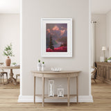 Alaska wall art print of a mountain sunset landscape painting depicting Denali and a field of fireweed wildflowers. The painting is titled "Denali Summer" by Karen Whitworth and is framed in a white wood picture frame. It is hanging on a beige wall behind a rustic farmhouse home decor table.