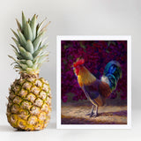 Rooster wall art print of a painting depicting a male chicken standing in front of a flowering bougainvillea bush. The rooster decor print is displayed next to a pineapple.