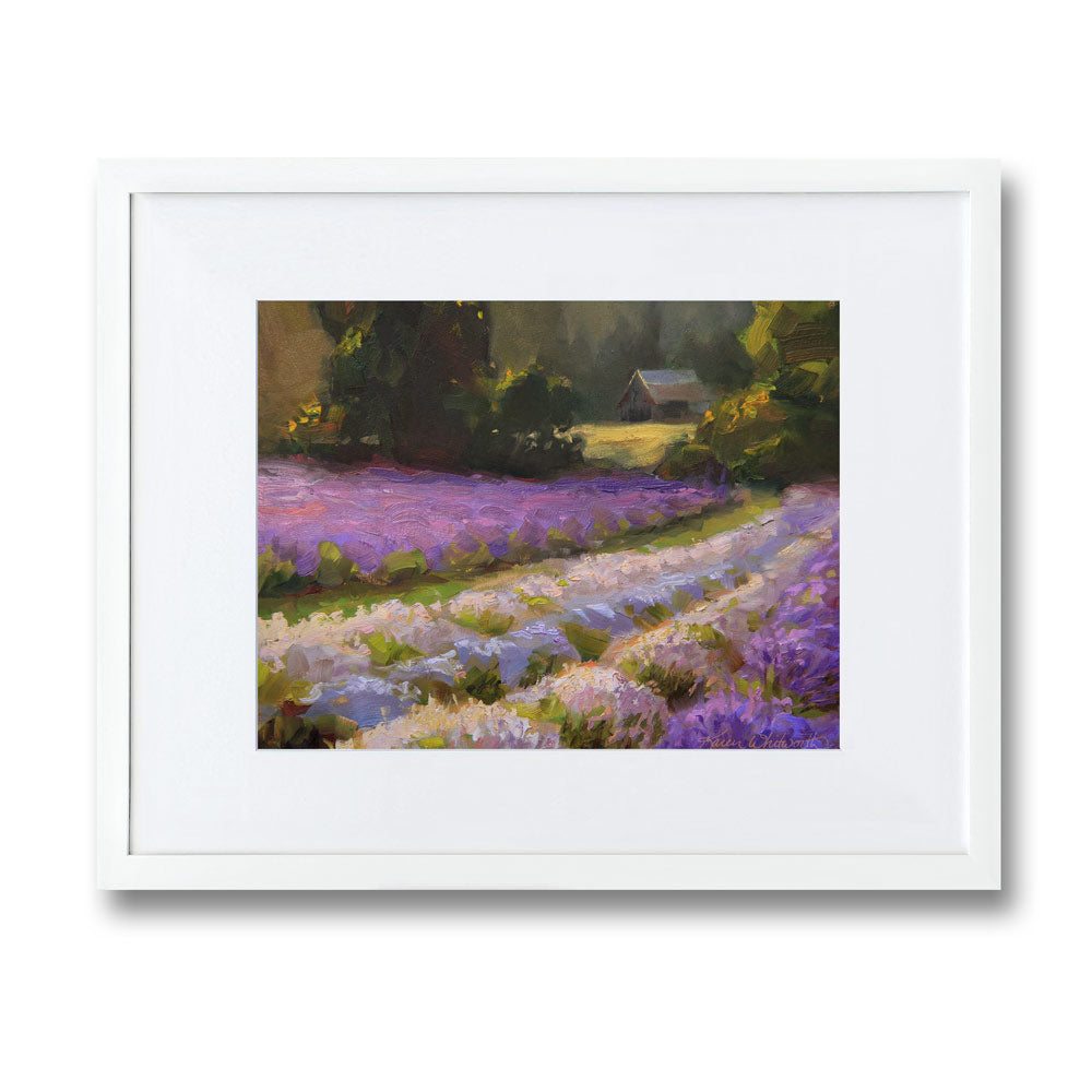 Framed lavender field wall art painting featuring a rural farmhouse landscape at sunset. In the background a rustic barn stands against a forest of green trees. The artwork is framed in a white wood picture frame and is hanging on a white wall.