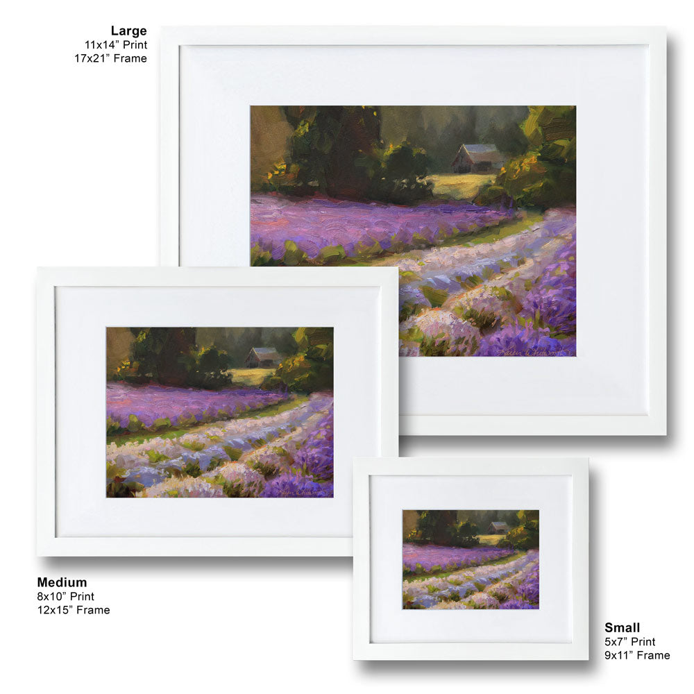 Framed lavender field wall art painting featuring a rural farmhouse landscape at sunset. In the background a rustic barn stands against a forest of green trees. The artwork is framed in a white wood picture frame and is hanging on a white wall. Three different sizes are displayed, small, medium, and large.