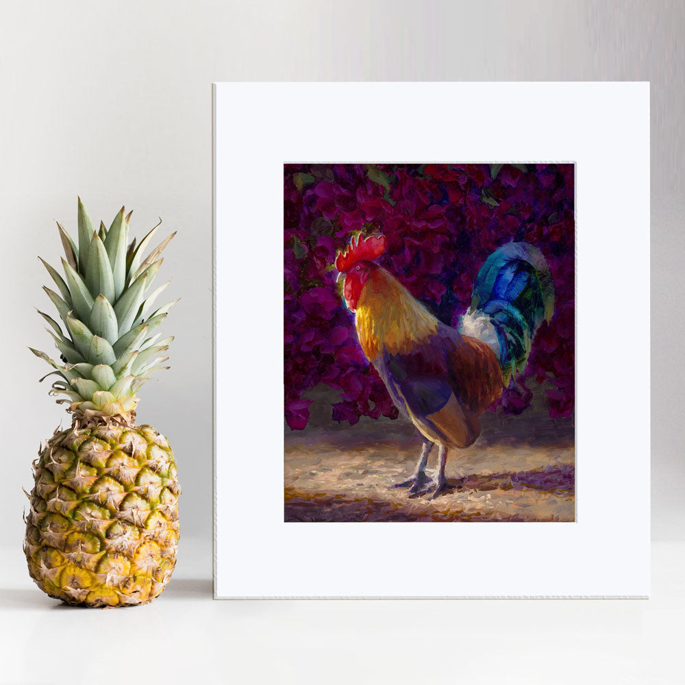 Rooster wall art print of a painting depicting a male chicken standing in front of a flowering bougainvillea bush. The rooster decor print is displayed next to a pineapple.