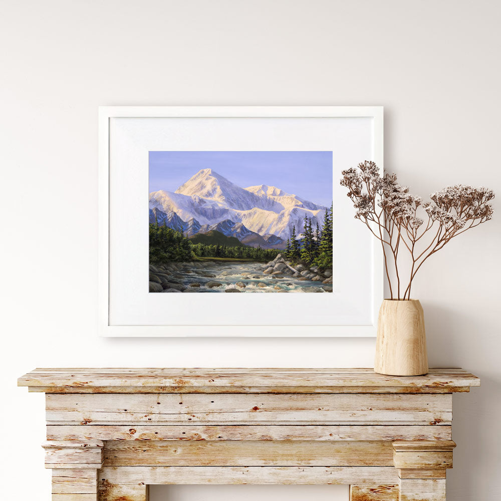 Alaska art print of Denali mountain wall art in a nature landscape painting. The artwork is displayed in a white wood picture frame over a rustic farmhouse decor fireplace mantel. 