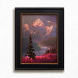 Alaska art featuring a painting of a mountain alpenglow sunset painting. The mountain landscape scene is framed and hanging on a white wall.