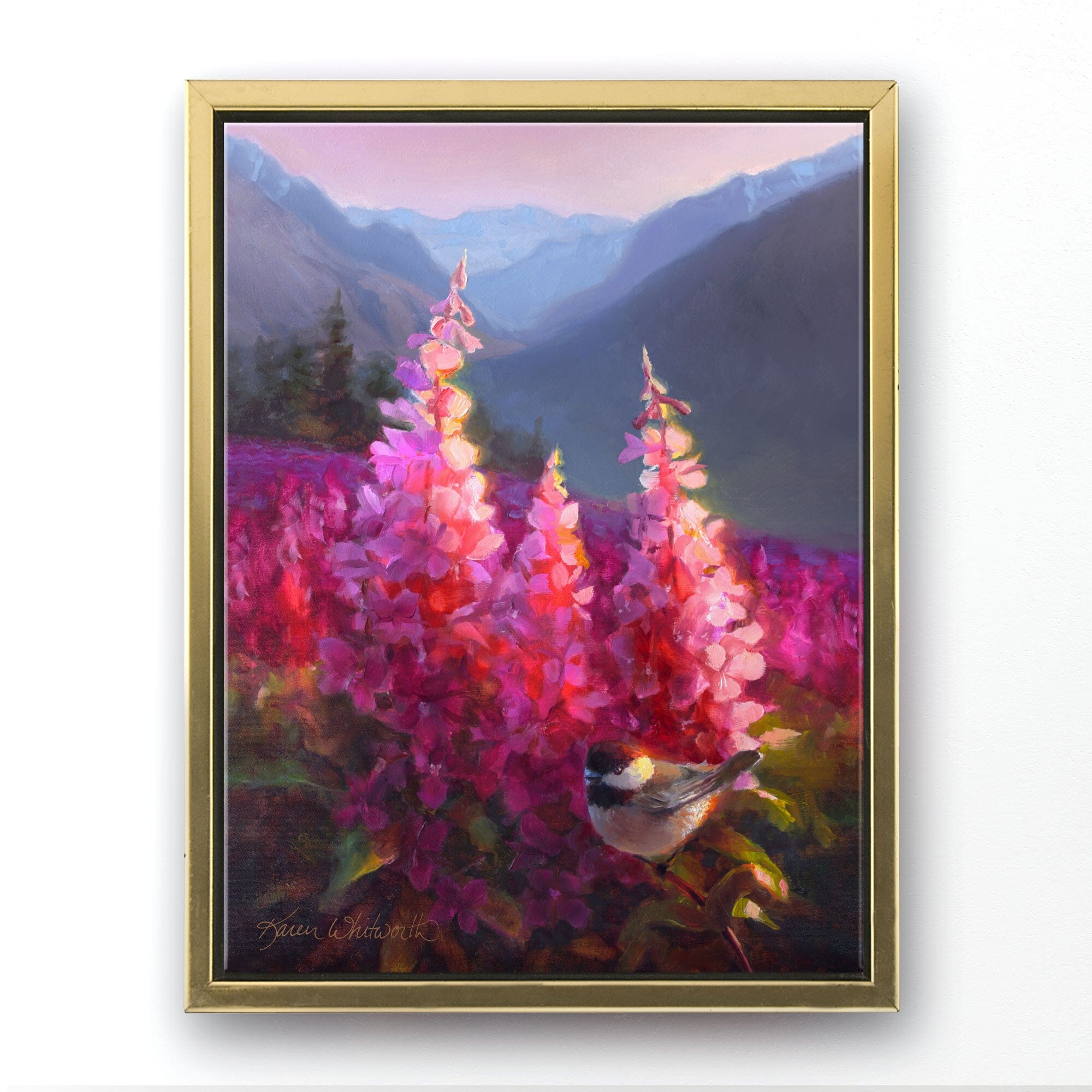 Alaska art on canvas of mountains with alpenglow on a meadow of fireweed flowers. This landscape painting is framed with a gold floater frame and is hanging on a white wall.