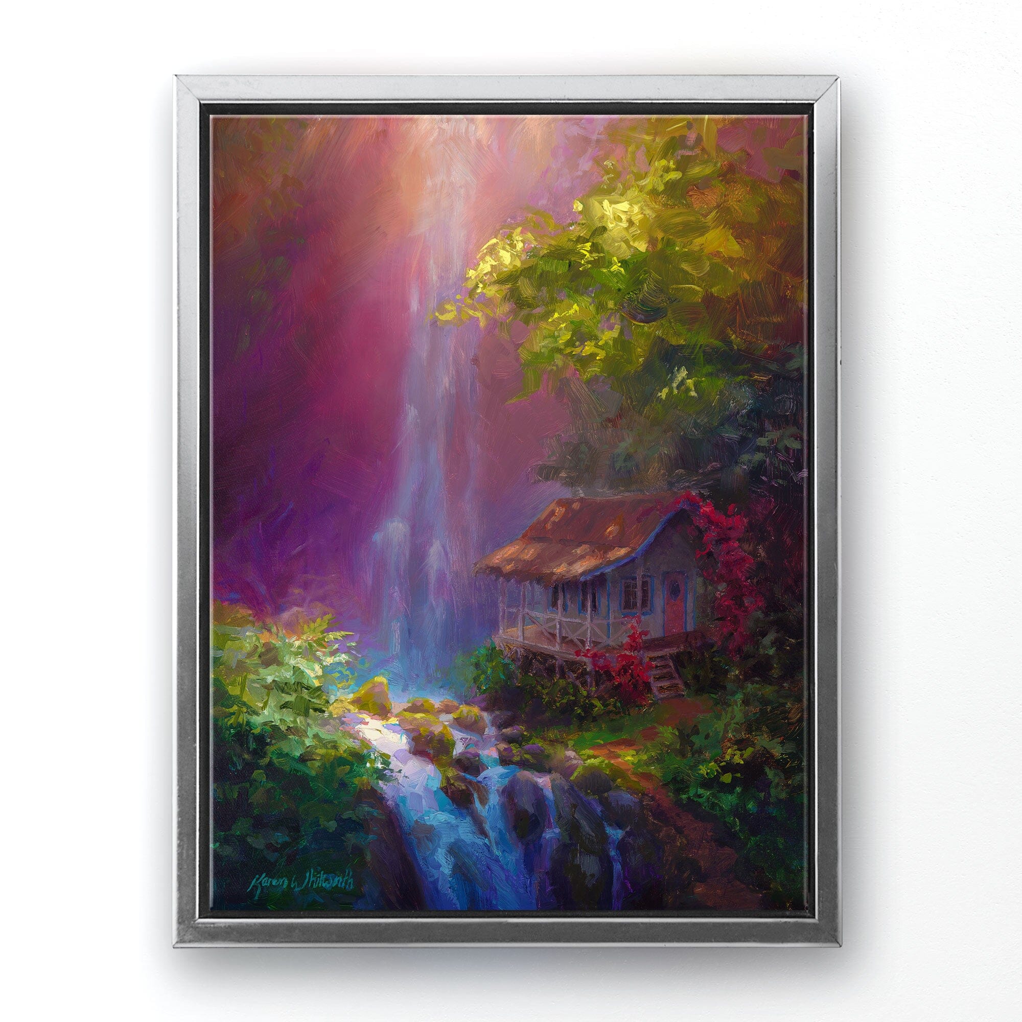 Landscape painting on canvas of Hawaiian waterfall by tropical artist Karen Whitworth titled "Healing Retreat". The canvas wall art is framed in a silver frame and is hanging on a white wall.