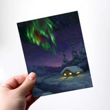 Northern lights greeting card with snowy log cabin by Alaska artist Karen Whitworth.